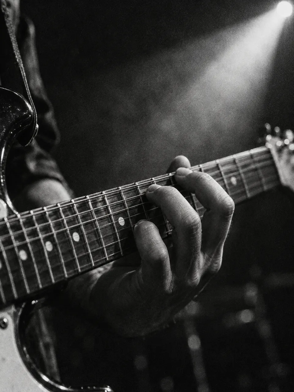 A hand pressing a chord on a guitar fretboard